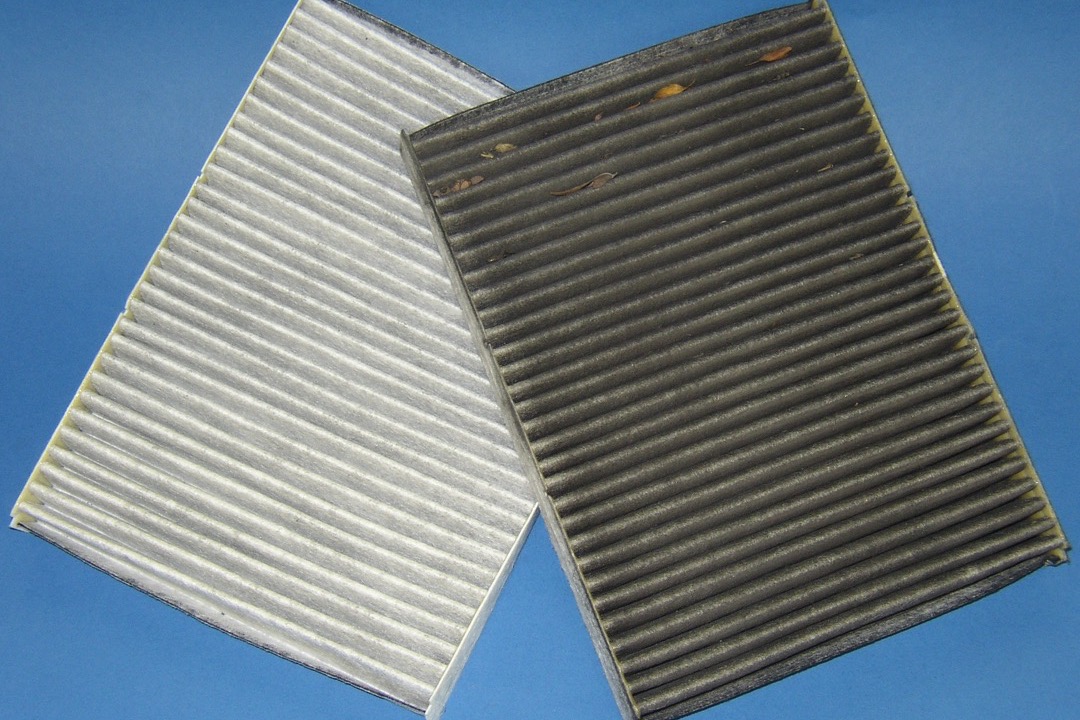 Cabin air filter being replaced behind a vehicle glove box in an automotive workshop