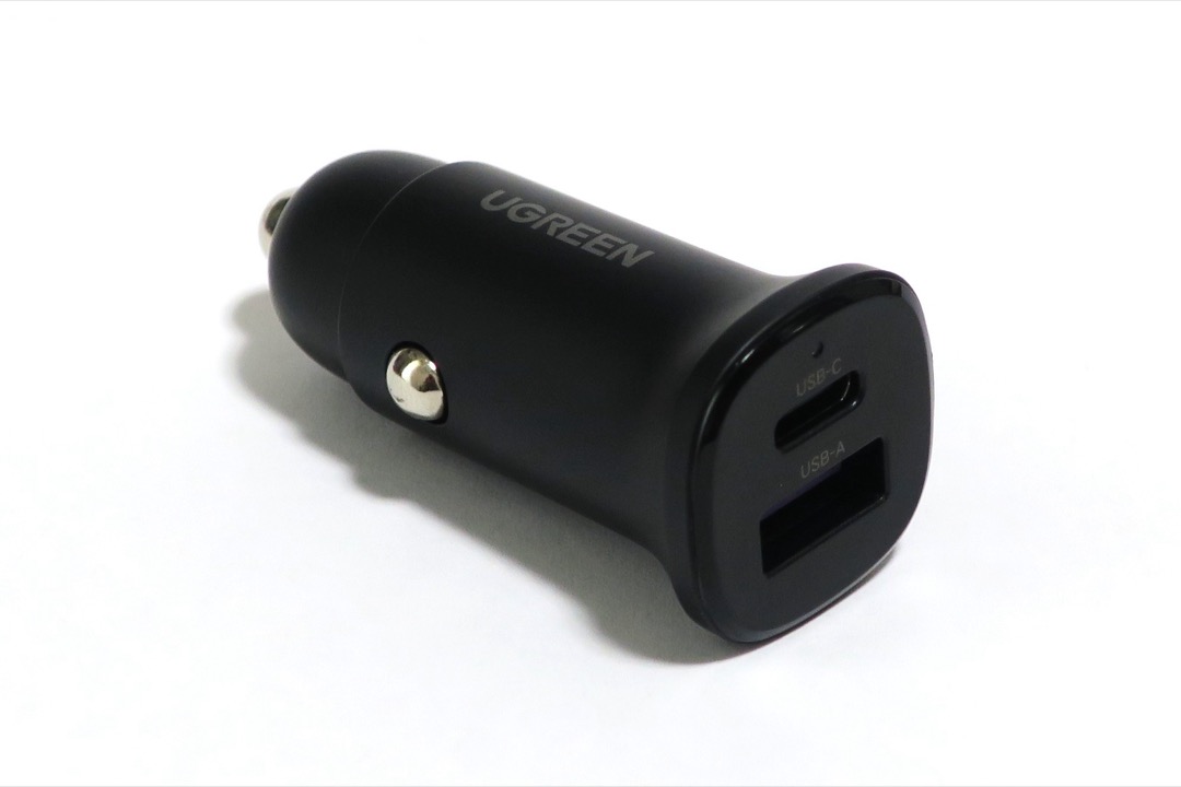 USB-C car charger plugged into a vehicle 12V socket charging a phone in the center console