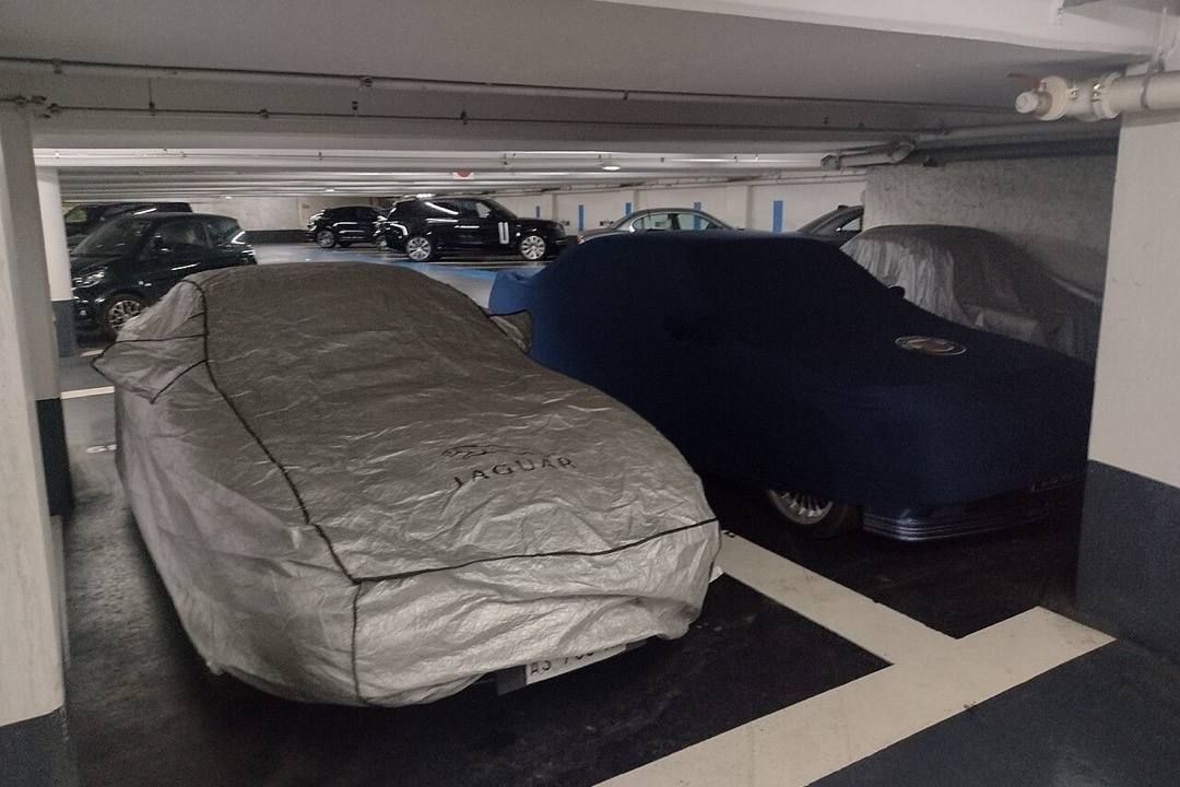 Silver car cover fitted over a sedan parked outdoors protecting against rain and UV exposure