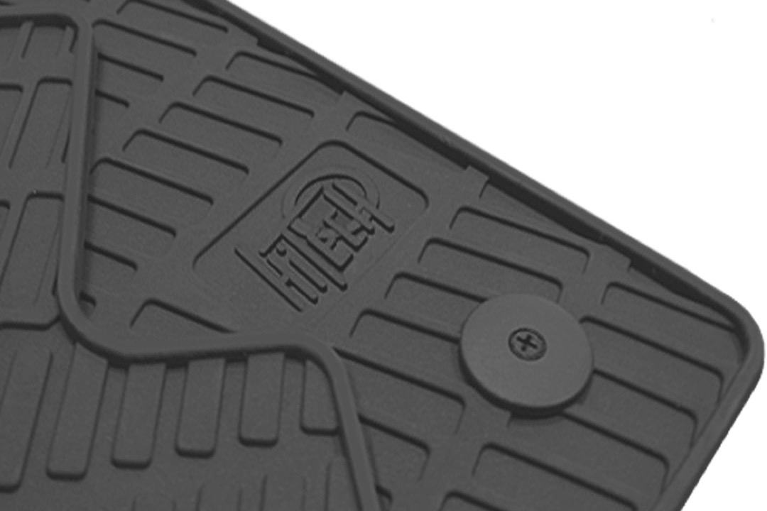 Black rubber all-weather car floor mat with deep channels installed in a vehicle footwell