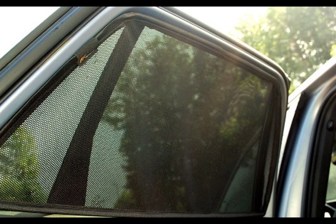 Silver reflective folding windshield sun shade installed inside a parked car