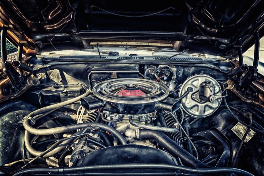 Engine air filter being inspected next to a car engine bay in a workshop