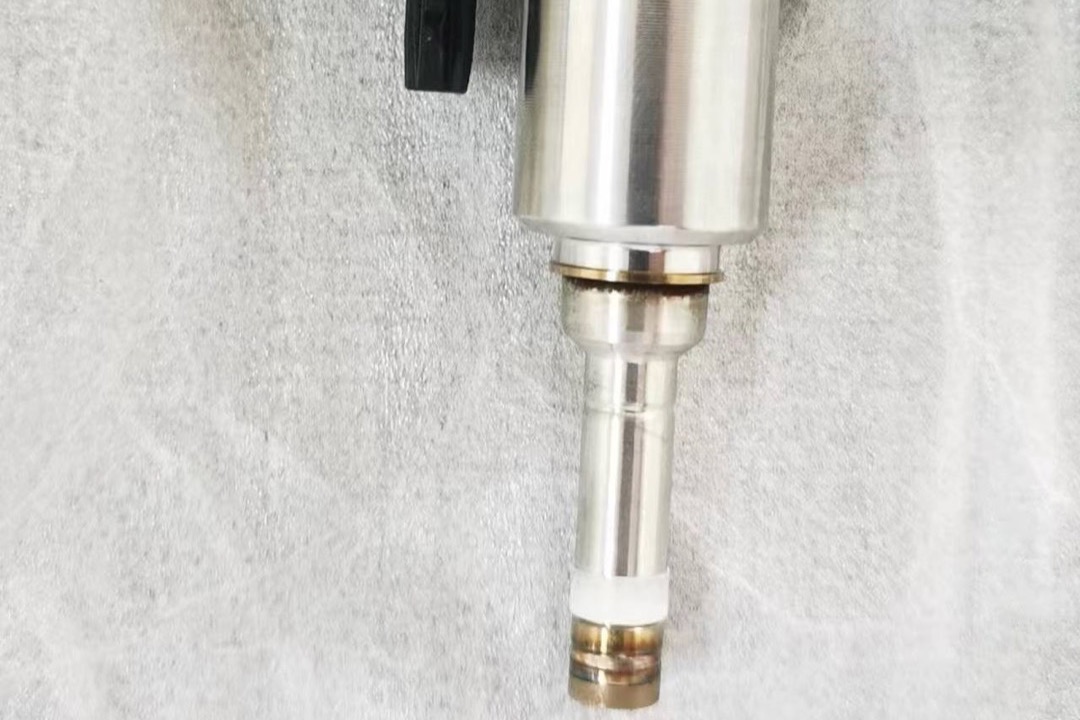 Bottle of fuel injector cleaner being poured into a car's fuel tank at a gas station