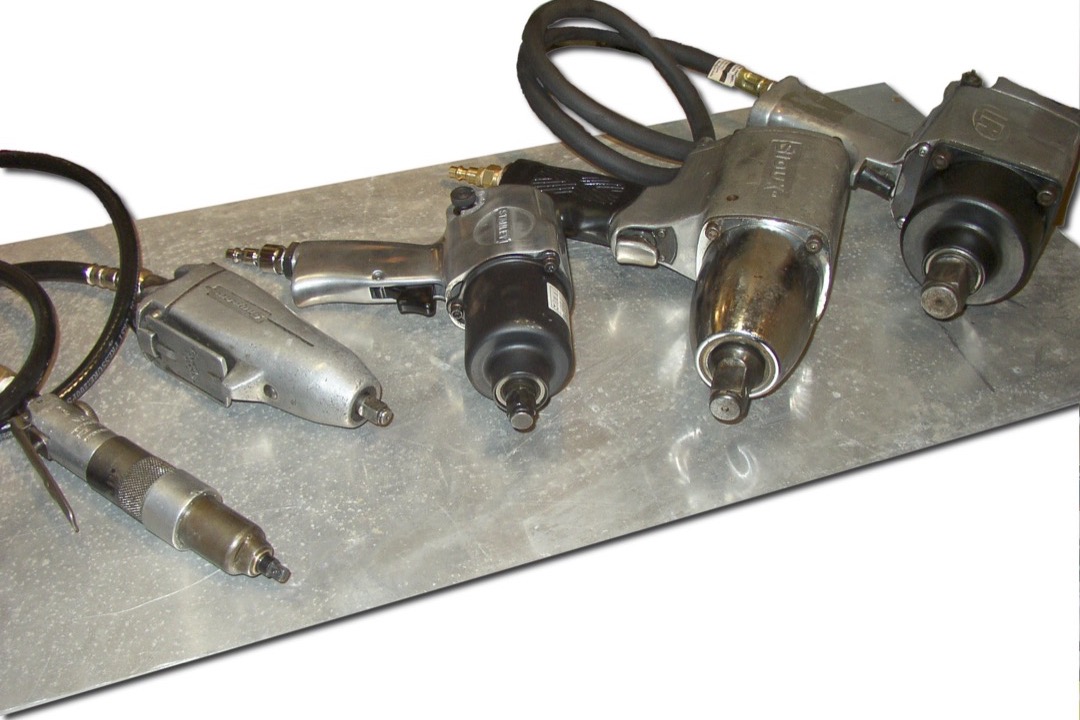 Cordless impact wrench being used to remove a lug nut from a vehicle wheel in an automotive shop