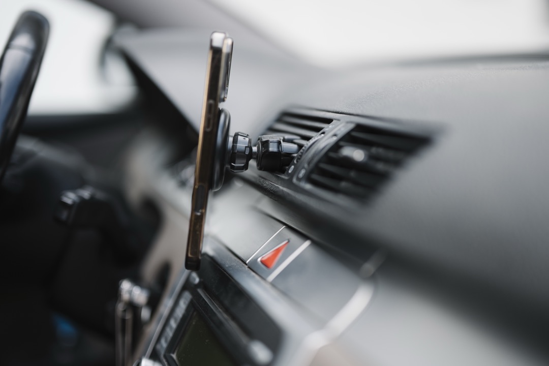 Smartphone held on a car dashboard mount running navigation while charging during a drive