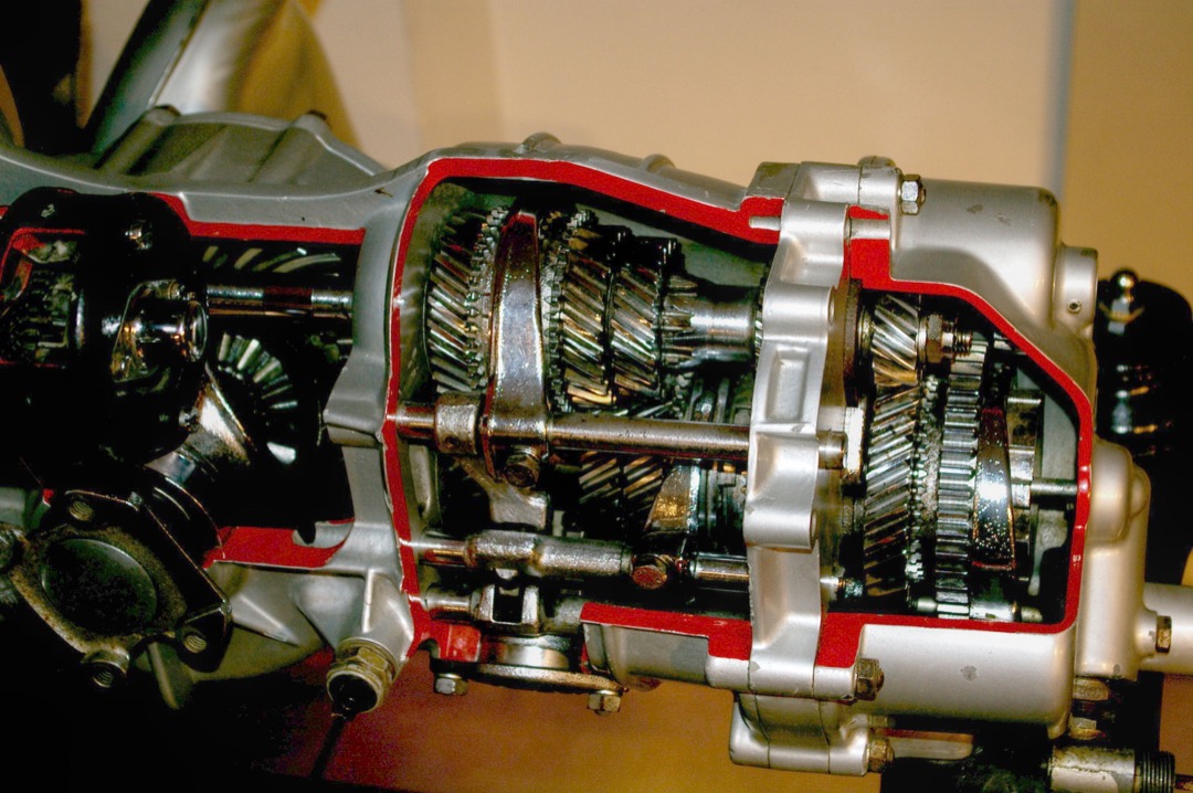 Cutaway view of a manual gearbox showing the gear cluster, shift forks, and brass synchronizer rings on the mainshaft