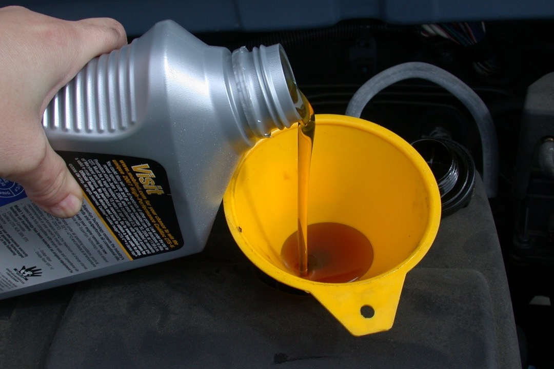 Five-quart jugs of high-mileage motor oil arranged on a workbench in an automotive service bay