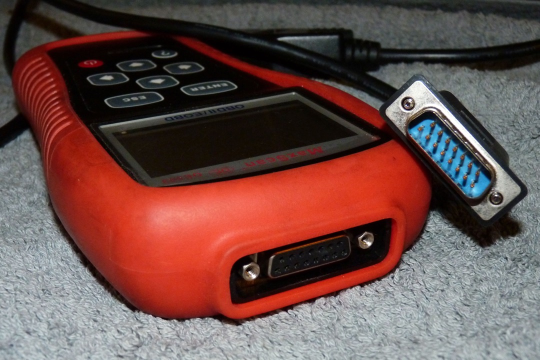 OBD2 scanner plugged into the diagnostic port under a car dashboard