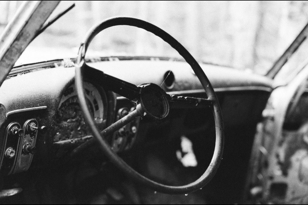 Black microfiber leather steering wheel cover installed on a car's steering wheel with contrast stitching