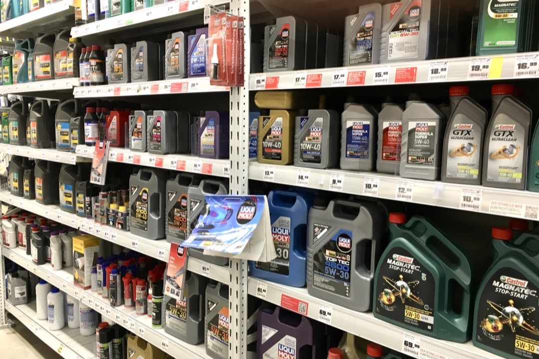 Bottles of full synthetic motor oil lined up on a workbench in an automotive service bay