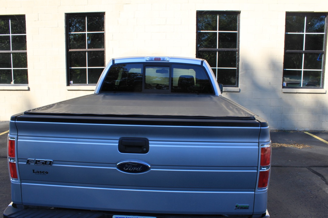 Hard folding tonneau cover installed on a pickup truck bed parked in a workshop