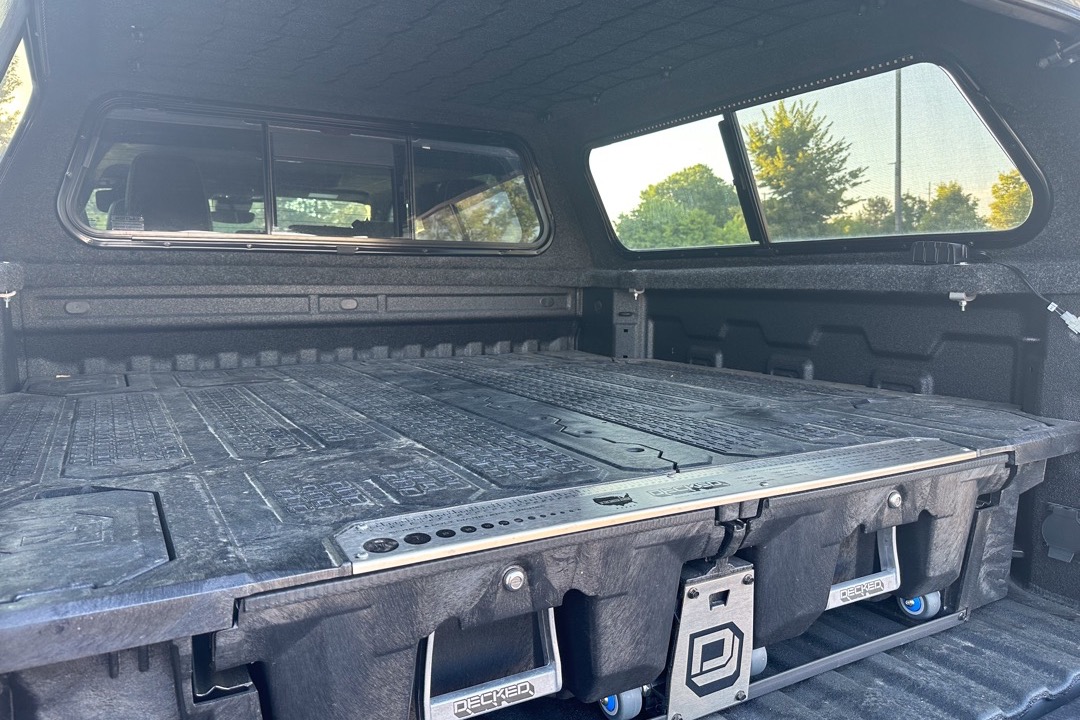Aluminum diamond plate crossover tool box mounted across the bed rails of a pickup truck