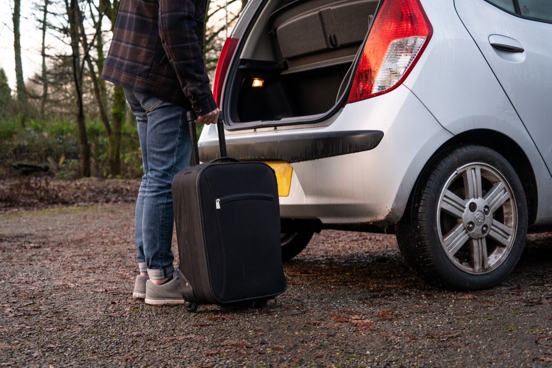 Collapsible fabric trunk organizer with multiple compartments holding tools and supplies in the cargo area of a car