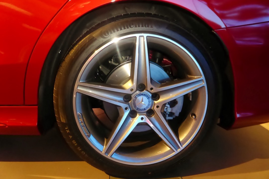 Alloy wheel being cleaned with foaming wheel cleaner spray and a detailing brush in an automotive shop