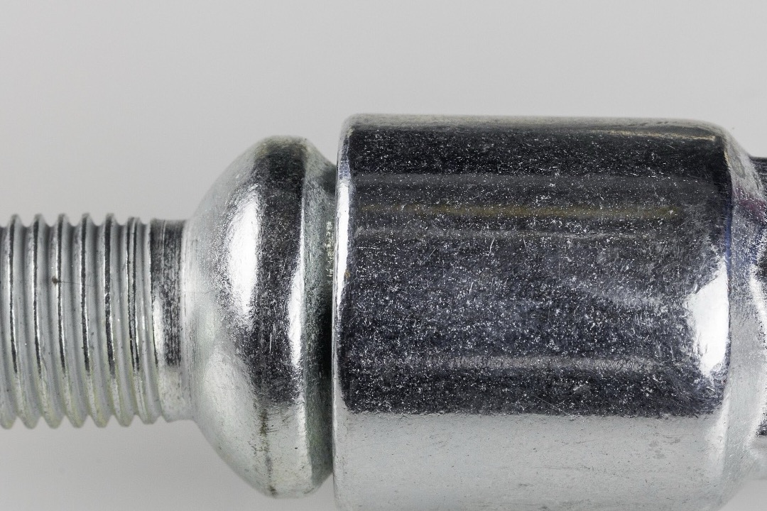 Set of chrome wheel locks with internal-pattern key on a workshop bench next to a lug socket