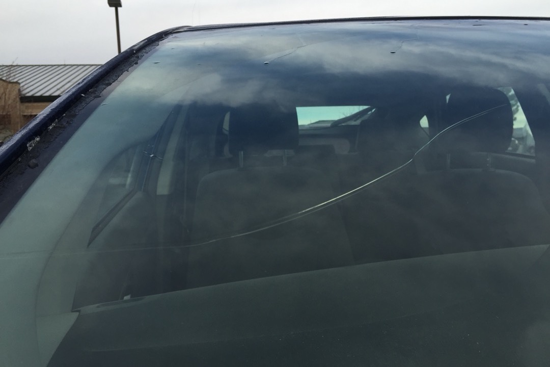 Bridge applicator and resin syringe being used to repair a small bullseye chip on a windshield