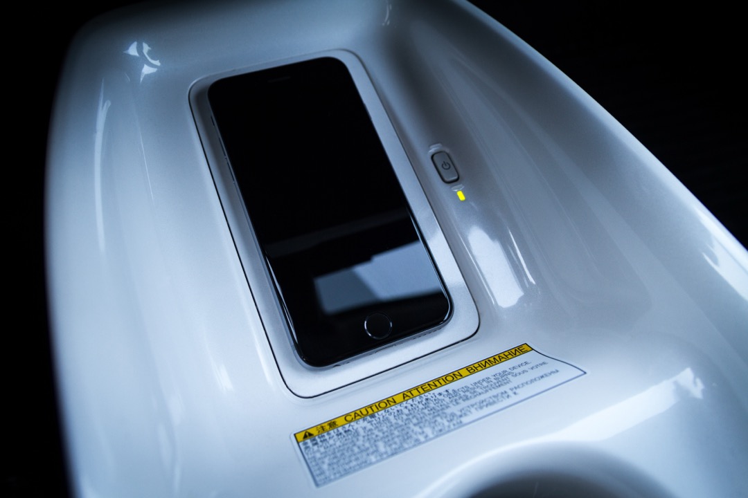 Smartphone charging on an in-car wireless charging tray set into a center console