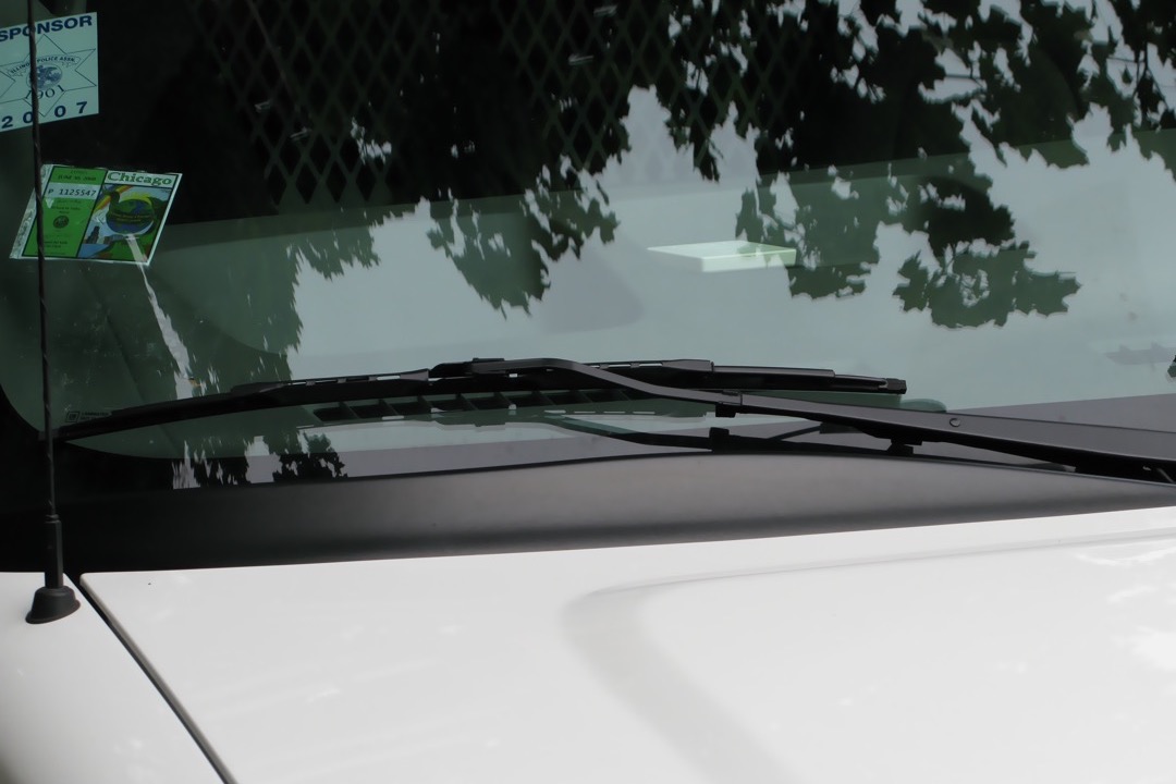 Close-up of a windshield wiper blade sweeping water off a wet glass surface