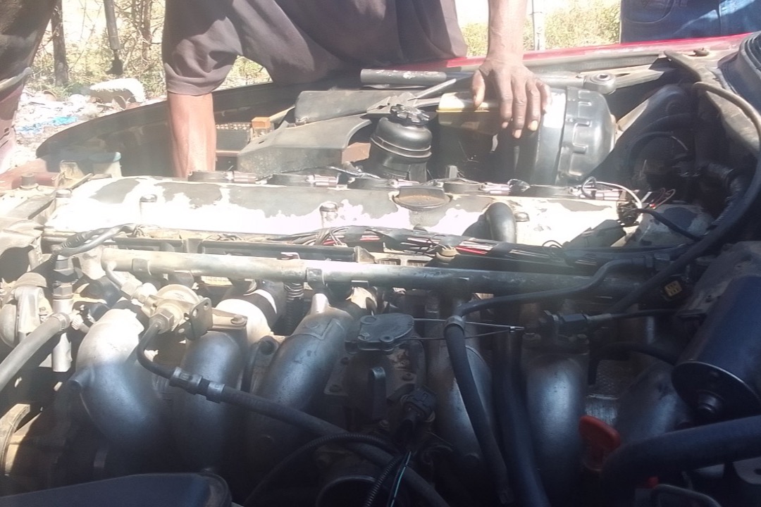 Mechanic performing routine maintenance on a car engine, showing the tools and components covered in a standard car maintenance schedule