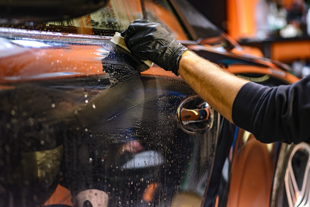 Detailing supplies arranged on a workbench including bottles of car wash soap, microfiber towels, and applicator pads