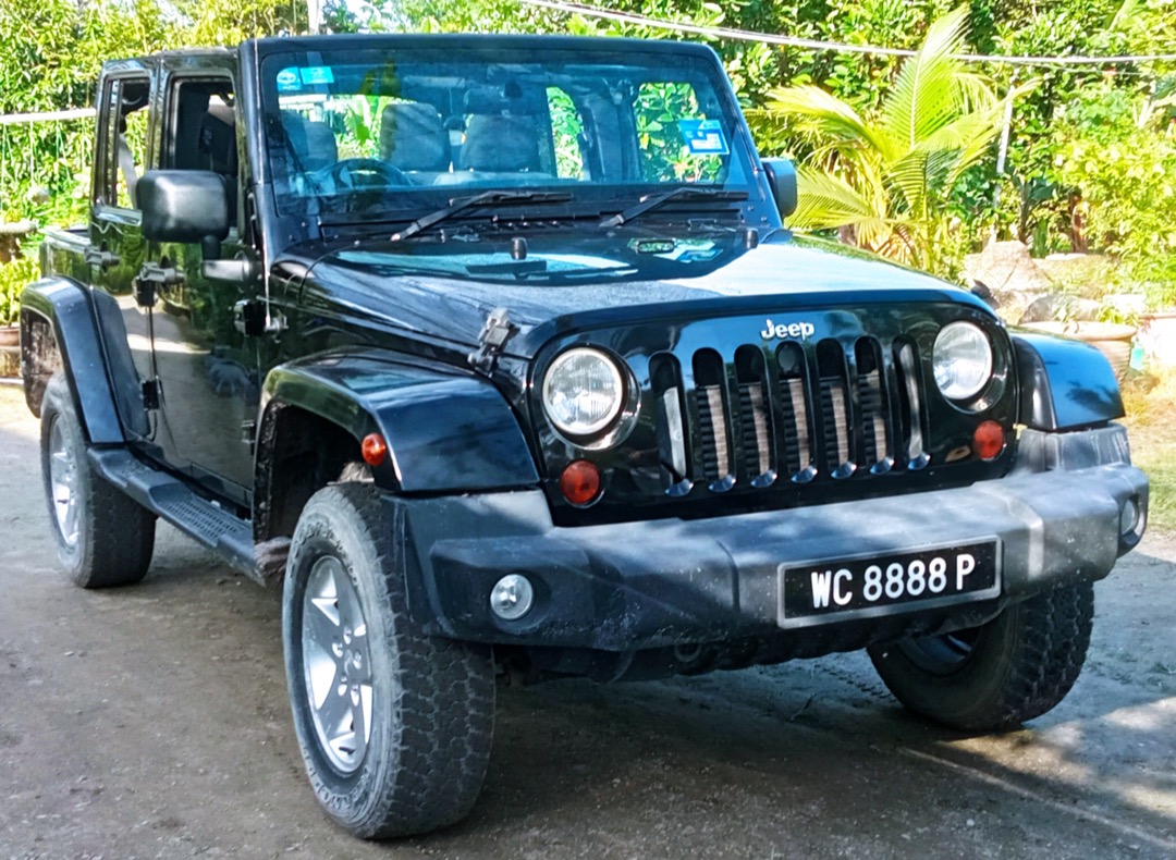 Front three-quarter view of a black 2012 Jeep Wrangler Unlimited JK showing its round halogen headlights, a common H13 application