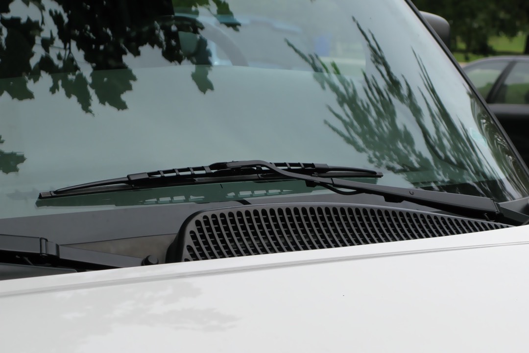 Close-up of a mechanic installing a new windshield wiper blade onto a wiper arm, demonstrating how to choose and fit the correct wiper for a vehicle