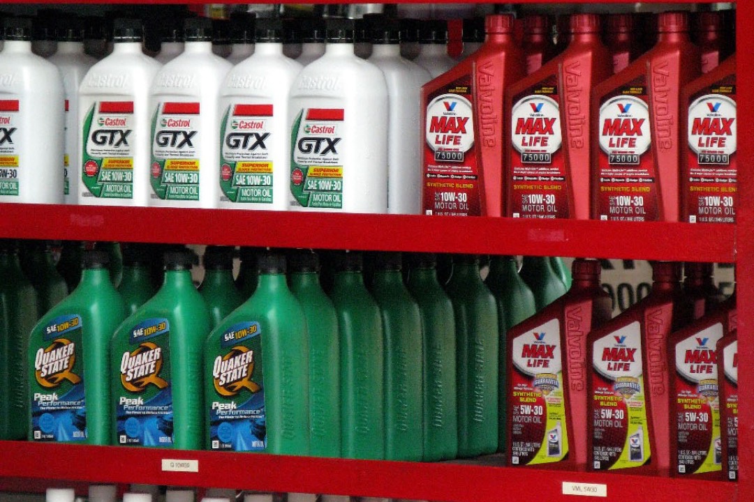 Multiple motor oil bottles of different brands lined up on a shelf