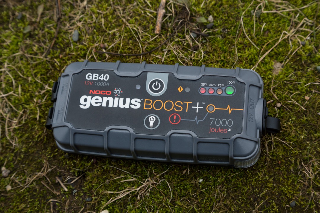 NOCO Genius Boost GB40 portable lithium jump starter connected to a car battery with red and black clamps